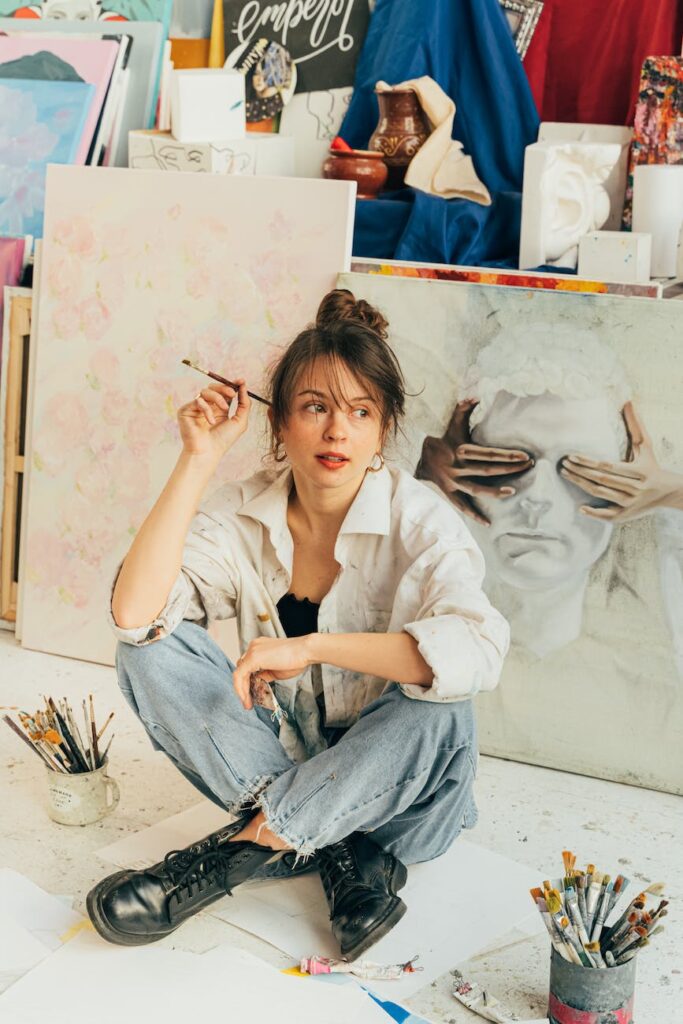 an artist sitting on the floor holding a paint brush