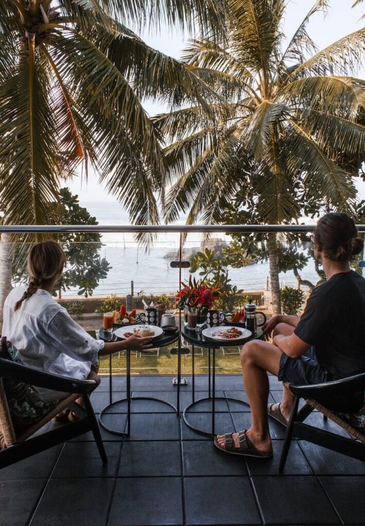 anonymous young couple resting on balcony during breakfast and enjoying sea view